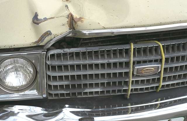 Frontal de un coche viejo, con el radiador sujeto con cuerdas